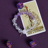 Purple and clear beaded bracelet with small dangling charm, stretch fit.