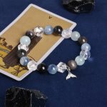 Beaded energy bracelet with blue and dark stones, clear crystal blocks, dangling angel charm