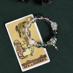 Beaded bracelet with clear beads, green stone beads, and silver sword drop