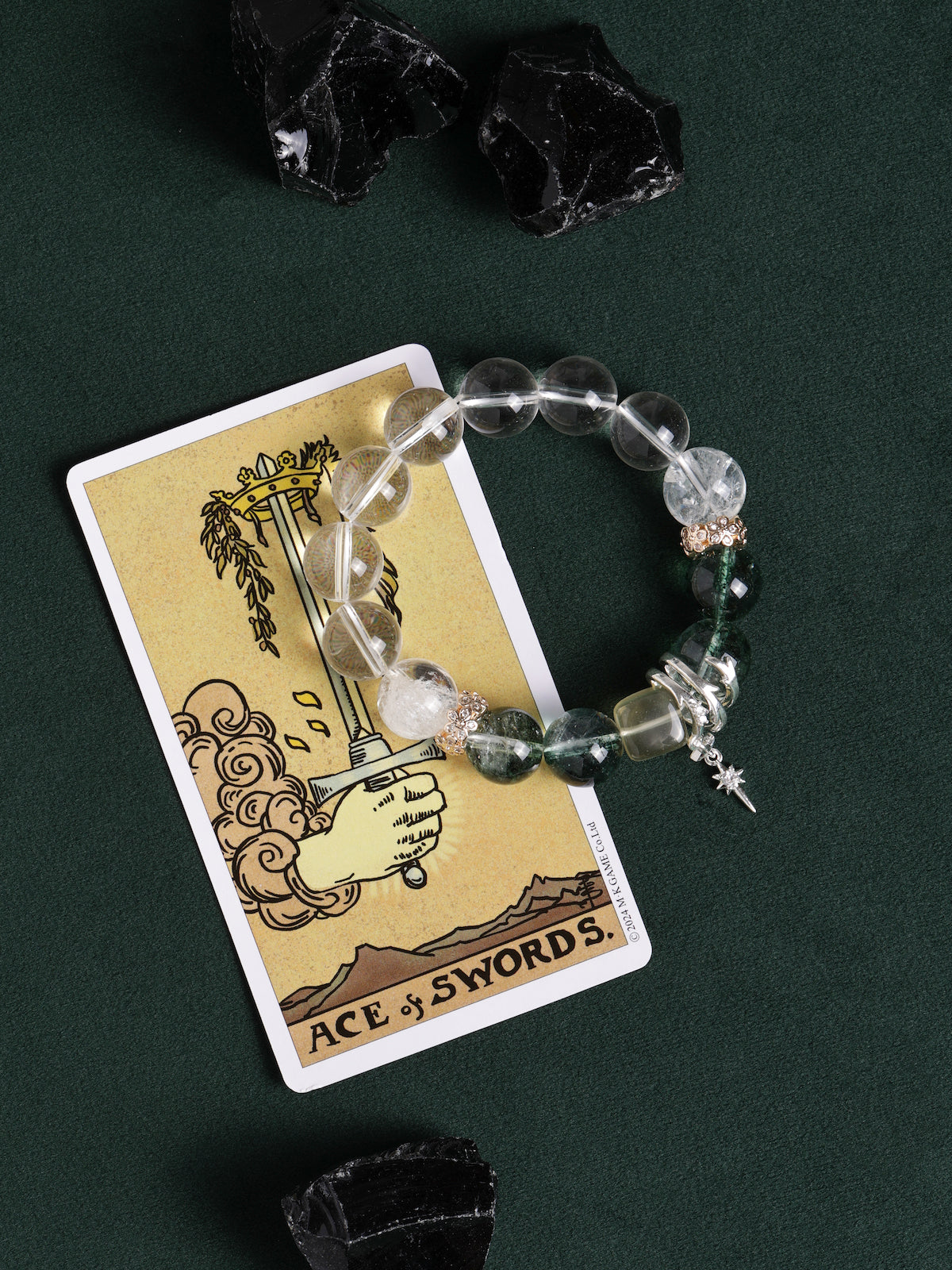Beaded bracelet with clear beads, green stone beads, and silver sword drop