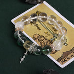 Beaded energy bracelet with clear beads, green stone beads, and dangling sword charm