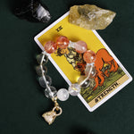 Beaded bracelet with orange-red and clear beads, silver accents, and gold heart charm