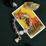 Beaded bracelet with orange-red and clear beads, silver accents, and gold heart charm
