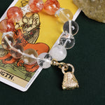 Energy bracelet with orange-red beads, clear round beads, silver links, and gold bag charm