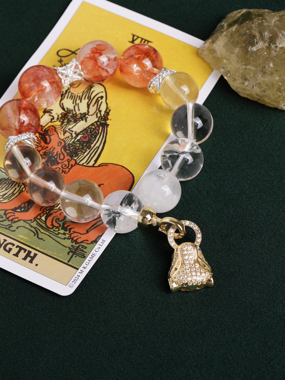 Energy bracelet with orange-red beads, clear round beads, silver links, and gold bag charm