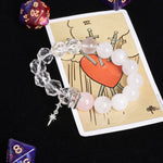 Crystal bead bracelet with clear and white-pink stones, dangling silver charm.