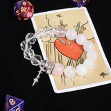 Crystal bead bracelet with clear and white-pink stones, dangling silver charm.