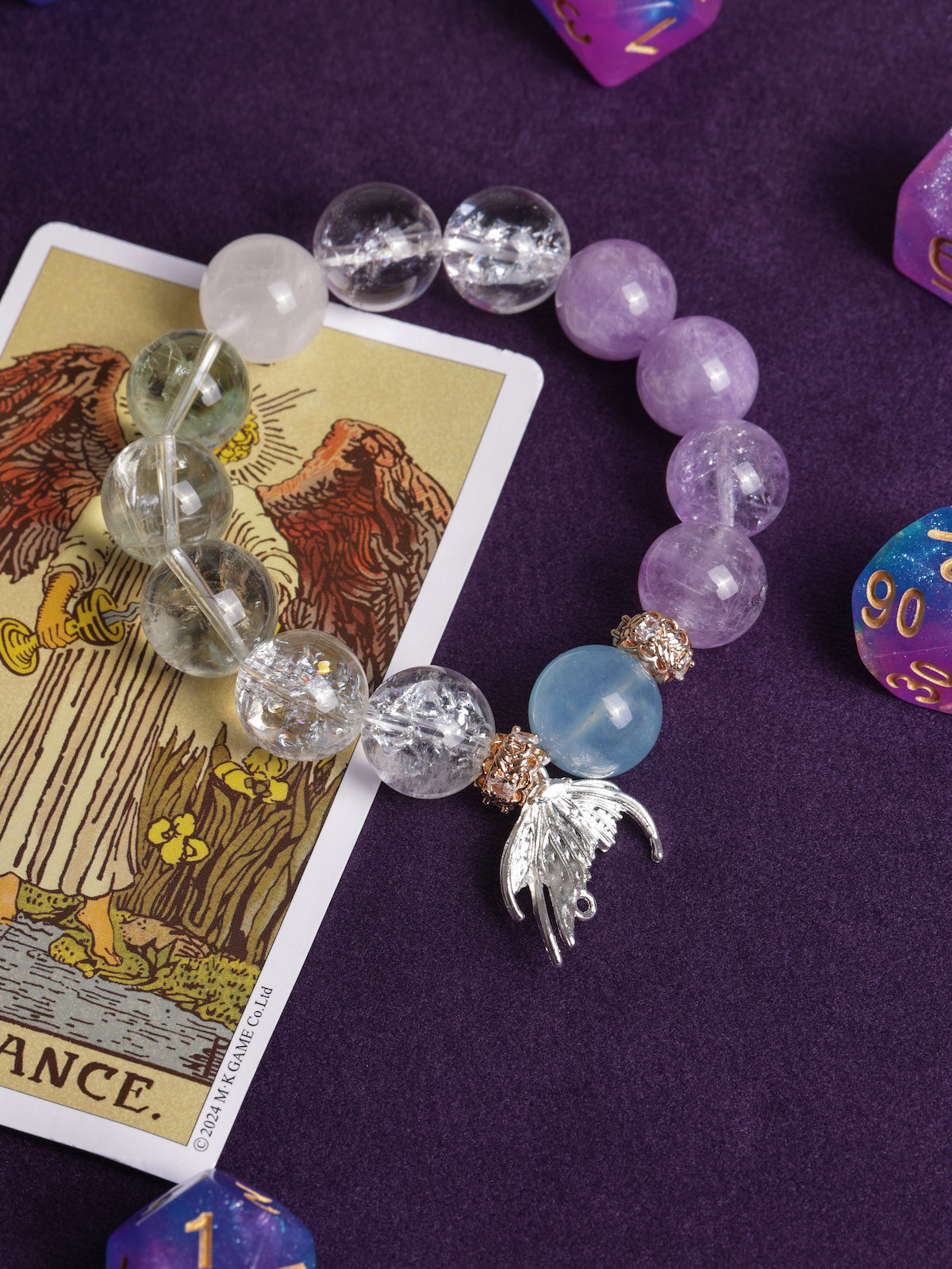 Beaded bracelet with clear, lilac, light-blue stones and gold-toned angel charm