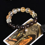 Beaded energy bracelet with alternating clear, amber, and dark beads and gold star charm