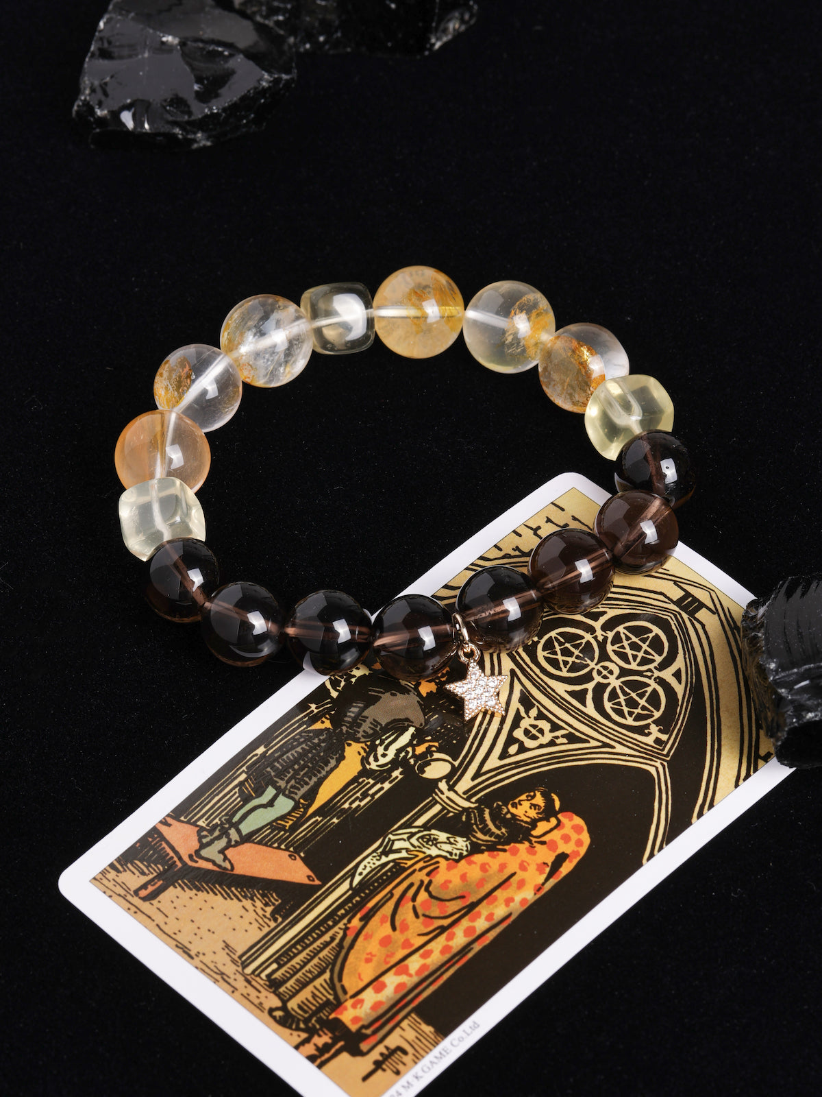 Beaded energy bracelet with alternating clear, amber, and dark beads and gold star charm