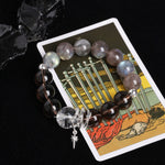 Energy bracelet with clear crystal centerpiece, dark striped beads, and star cross charm