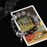 Energy bracelet with clear crystal centerpiece, dark striped beads, and star cross charm