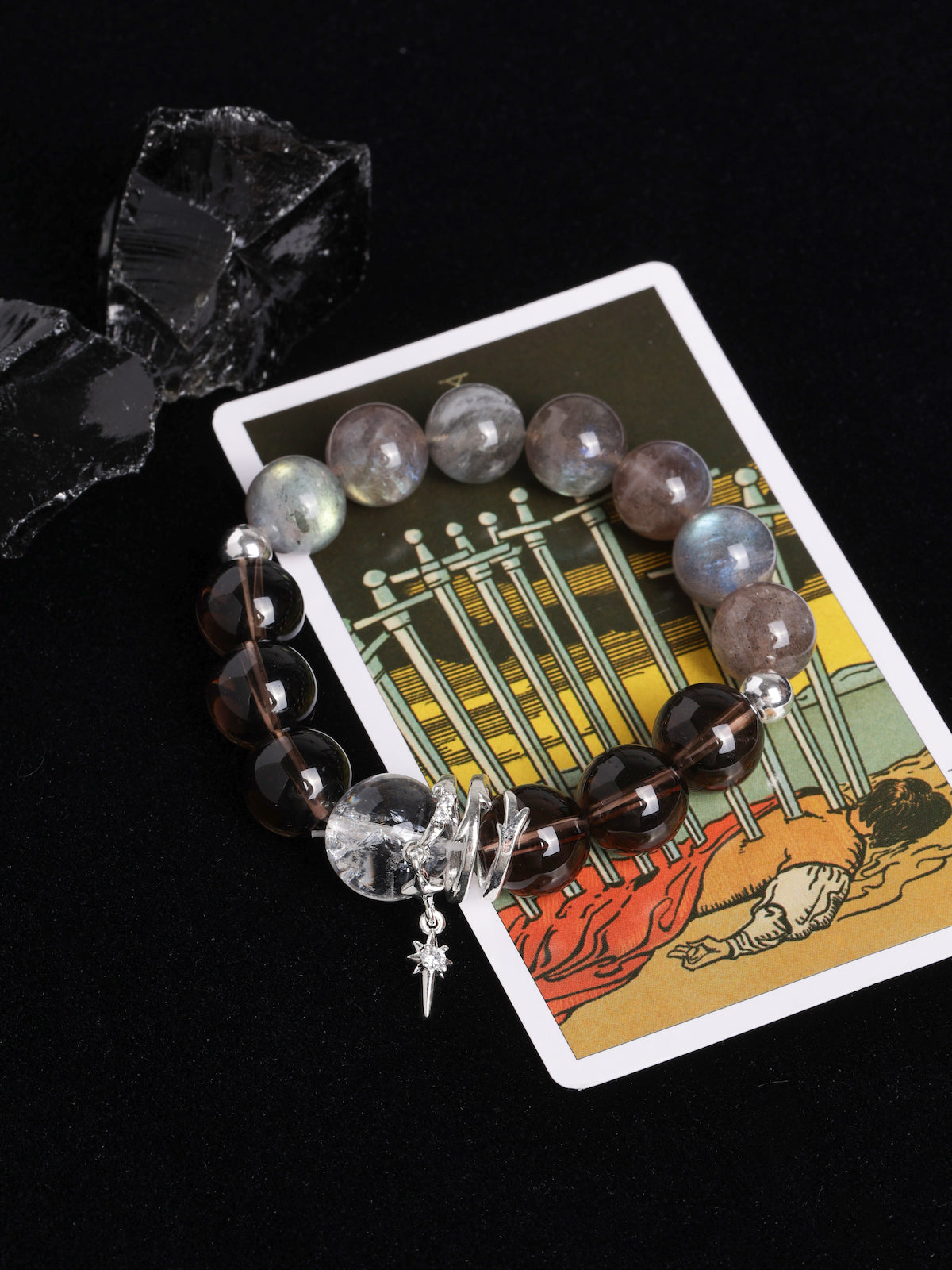 Energy bracelet with clear crystal centerpiece, dark striped beads, and star cross charm