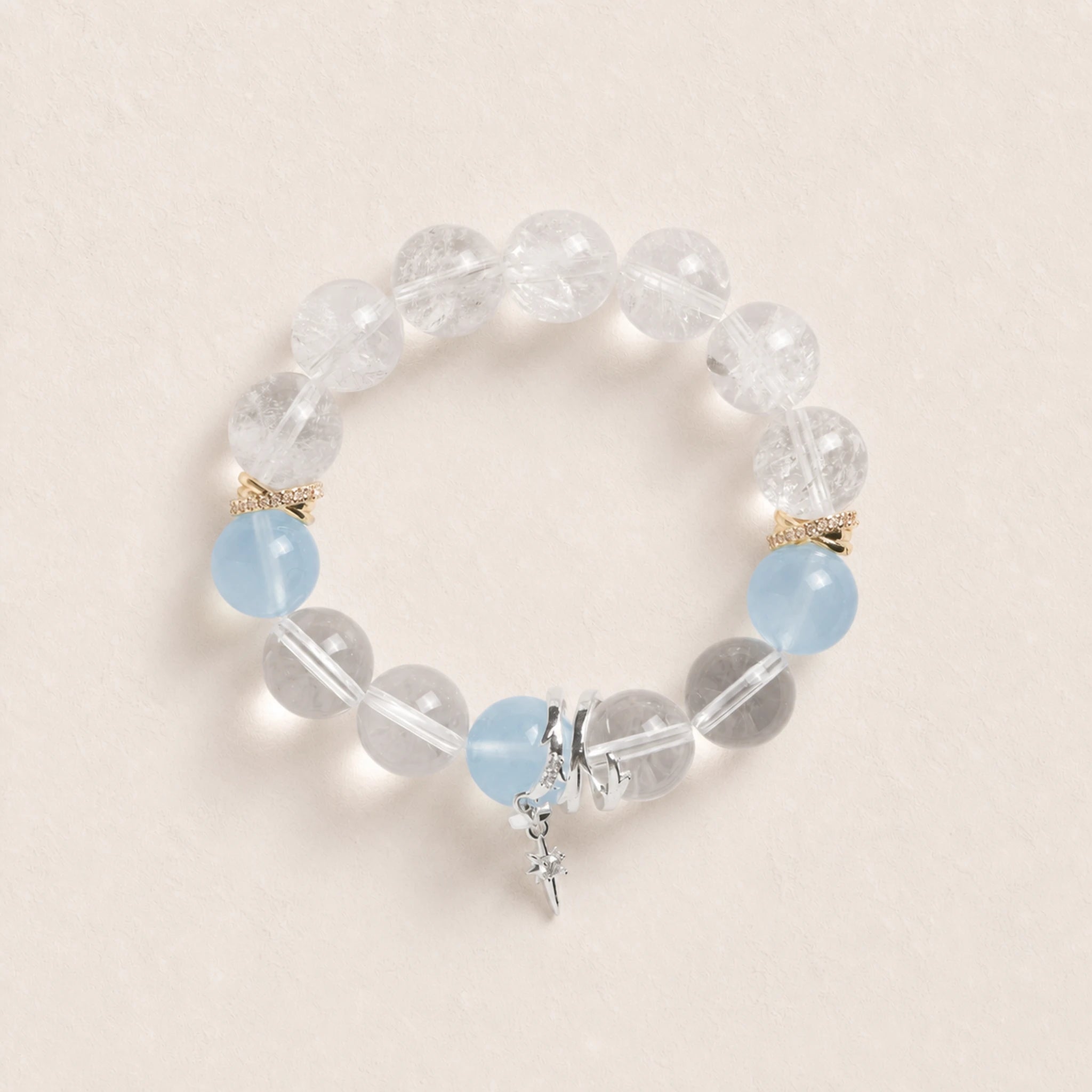 Beaded energy bracelet with clear stones, light blue accents, gold spacers, silver charm