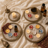 Scented candle ritual tray set with four lit candles, crystal pieces, oil bottles